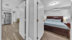 A bedroom with a wooden bed, a nightstand, and a bedside table. - 3Bed Modern Home Family Friendly Heated Pool (Fort Lauderdale)