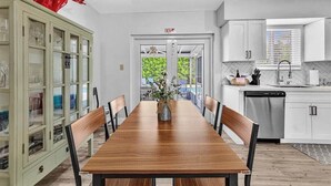 A dining area with a wooden table, chairs, a cabinet with glass doors, and a red sculpture. - 3Bed Modern Home Family Friendly Heated Pool (Fort Lauderdale)