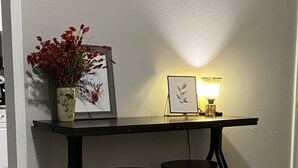 A dining area with a black table and two stools, a vase with red flowers, and a framed picture on the wall. - New!! Woodcrest Cottage - Close to Tri-Cities (Kingsport)