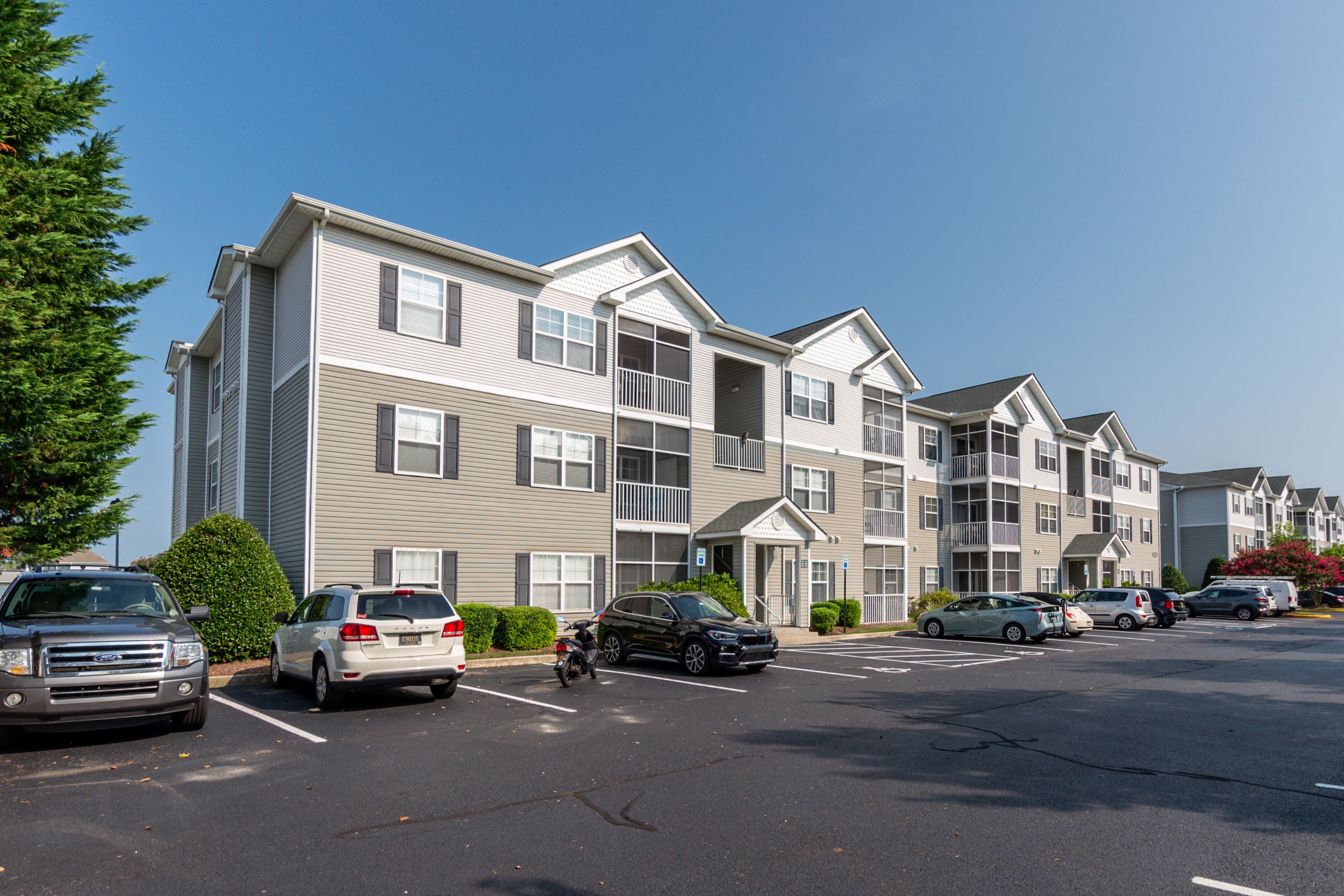 A multi-story apartment building with a parking lot in front.