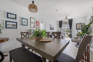 Un coin repas avec une table en bois, des chaises et un ventilateur de plafond.