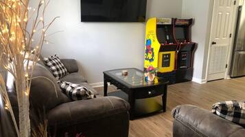 Ein Wohnzimmer mit einer Couch, einem Couchtisch und einem an der Wand befestigten Flachbildfernseher.