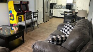 A living room with a sofa, a coffee table, and a gaming console.