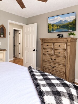 A bedroom with a bed, a dresser, a painting, and a door leading to another room. - RARE - 2 miles to Dollywood - Arcades & Much More (Sevierville)