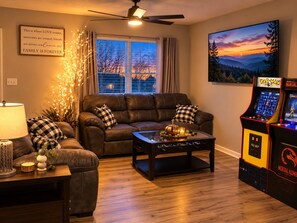 A living room with a leather sofa, a coffee table, and a Pac-Man arcade machine. - RARE - 2 miles to Dollywood - Arcades & Much More (Sevierville)
