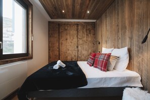 Una camera da letto con un letto grande, pareti in legno, una finestra e vista all'esterno.