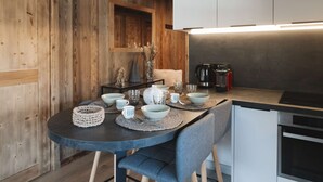 Eine moderne Küche mit Essbereich, ausgestattet mit einem runden Tisch, Schüsseln, Tassen und einer Kaffeemaschine.