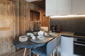 Una cucina moderna con zona pranzo, che include un tavolo rotondo con ciotole, tazze e una macchina da caffè.