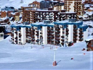 A snow-covered residential area with multi-story buildings, likely a ski resort.