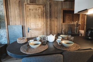 Una tavola da pranzo apparecchiata con ciotole, tazze, un teiera e bicchieri, con una porta in legno e decorazioni rustiche sullo sfondo.