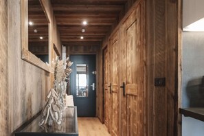 Ein Holzflur mit einem Spiegel, einer Vase mit getrockneten Blumen und einer Tür zu einem anderen Raum.