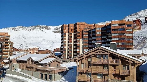 Ein Skigebiet mit Holzbauten und einem schneebedeckten Berg im Hintergrund.