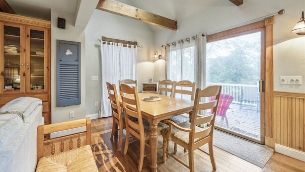 Un comedor acogedor con una mesa y sillas de madera, un armario empotrado y vistas al exterior a través de un ventanal.
