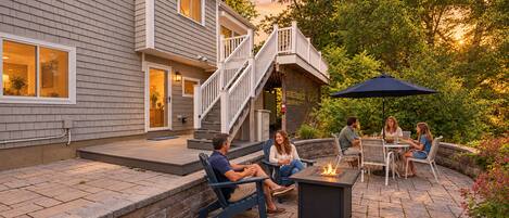A patio area with outdoor seating, a fire pit, and a staircase leading to a deck.