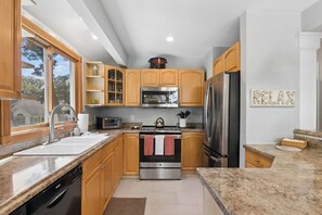 A modern kitchen with wooden cabinets, stainless steel appliances, and a granite countertop.