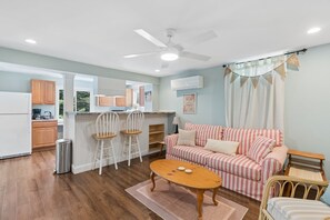 A modern kitchen with white cabinets, a dining area with striped furniture, and a ceiling fan. - Walk to Downtown OGT! (Ogunquit)