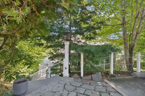 A stone staircase leading up to a white fence with a lantern post, surrounded by trees and greenery. - Walk to Downtown OGT! (Ogunquit)