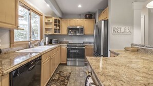 Una cocina moderna con encimeras de granito, electrodomésticos de acero inoxidable y armarios de madera.
