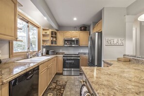 A modern kitchen with granite countertops, stainless steel appliances, and wooden cabinets.