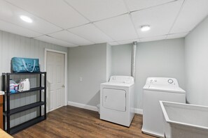 A laundry room with a washing machine, dryer, and a shelf with cleaning supplies.