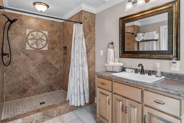 Une salle de bain avec une douche, un lavabo et un grand miroir.