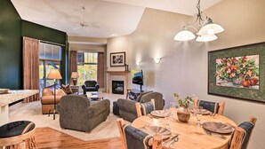 Ein gemütliches Wohnzimmer mit Kamin, bequemen Sitzgelegenheiten und einem Essbereich mit Holztischen und -stühlen.
