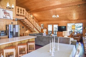 A wooden cabin interior with a kitchen, dining area, and living room.
