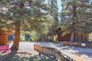 A rustic cabin with a wooden deck and a gravel path leading to it.