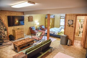 A cozy room with a bed, a wooden dresser, a television, and a fireplace.
