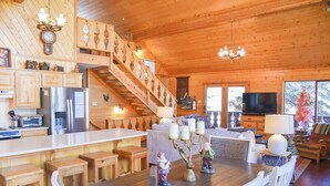 Une cabane en bois spacieuse comprenant une grande salle à manger, une cuisine et un salon.