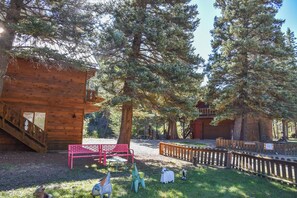 A rustic cabin with a wooden staircase and a red bench.