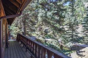 Une terrasse en bois dotée d’une rambarde, qui offre une vue sur une zone boisée.