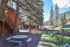 A wooden cabin with a deck and a picnic table in a forested area.