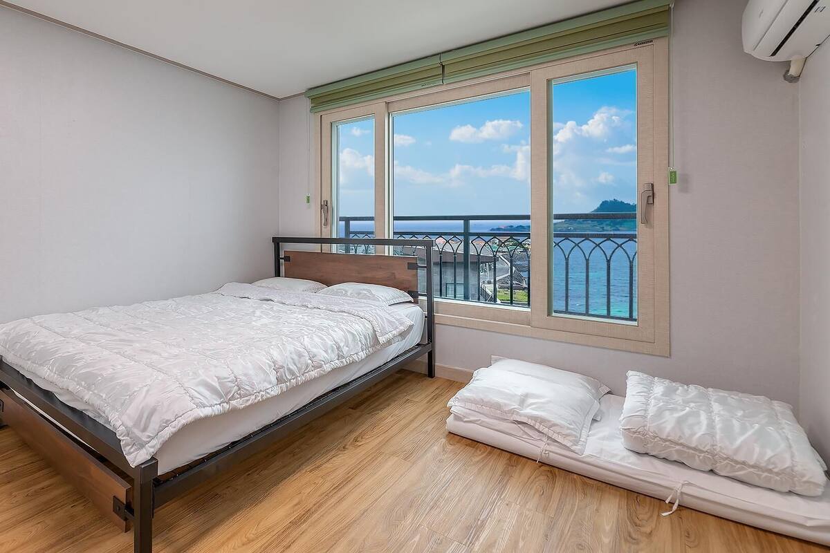 Et soveværelse med seng, et vindue med havudsigt og en balkon.