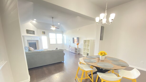 A modern dining area with a round table, yellow chairs, and a chandelier. - Beautiful Lake House in Garland Texas (Garland)