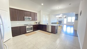 A spacious kitchen with dark brown cabinets, a stainless steel microwave, an oven, and a dishwasher. - Beautiful Lake House in Garland Texas (Garland)