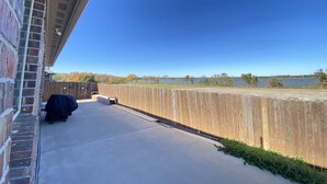 A patio with a view of a lake, a wooden fence, and a brick wall. - Beautiful Lake House in Garland Texas (Garland)