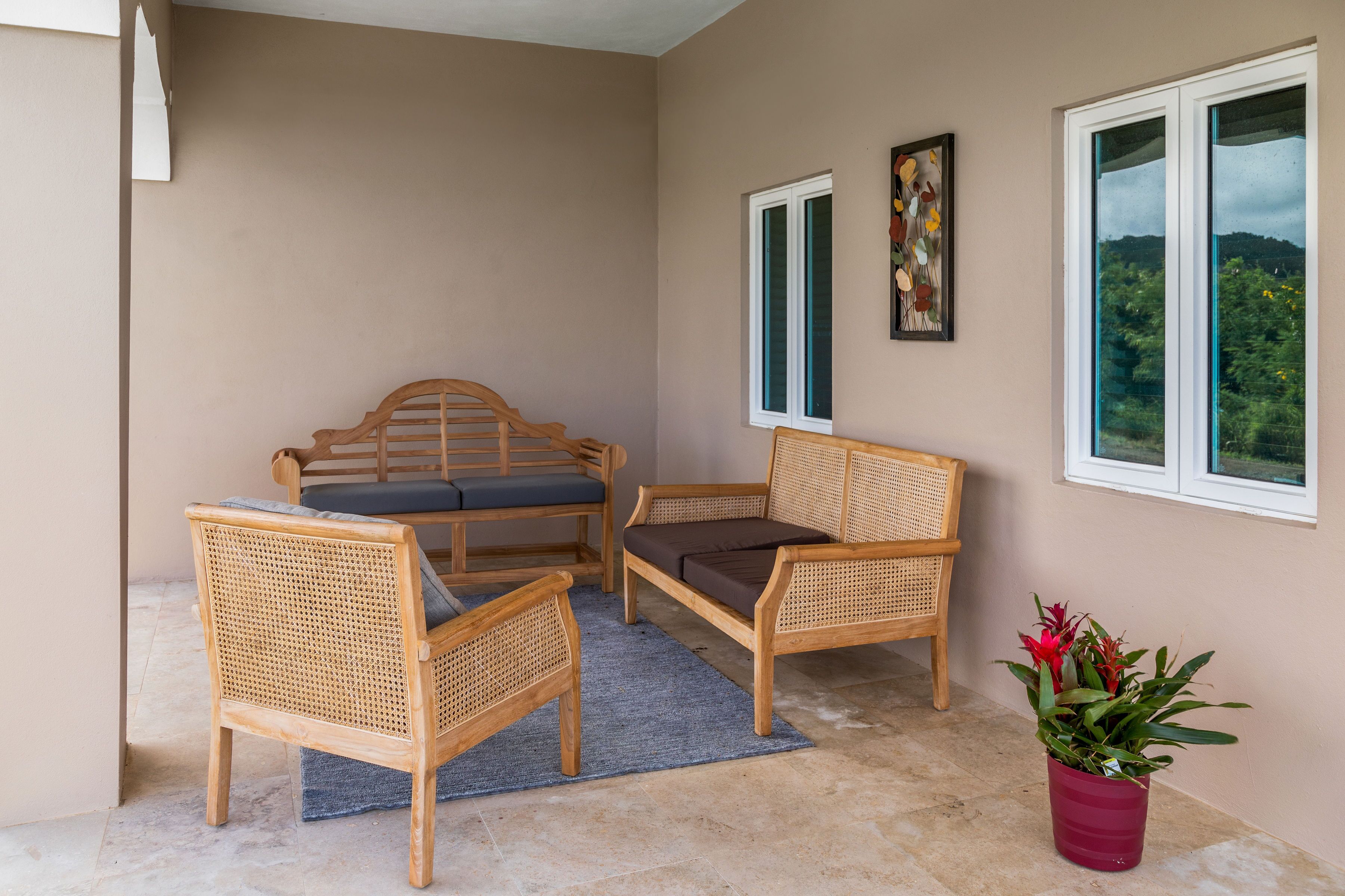 Une pièce comprenant deux fauteuils en osier, une petite table et une plante en pot.