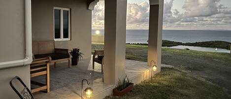 A covered outdoor seating area with a view of the ocean.