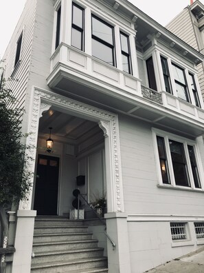 A two-story building with a prominent entrance, a balcony, and a staircase leading to the entrance. - Elegant 2 bedroom 2 bath SF Flat in beautiful neighborhood (San Francisco)