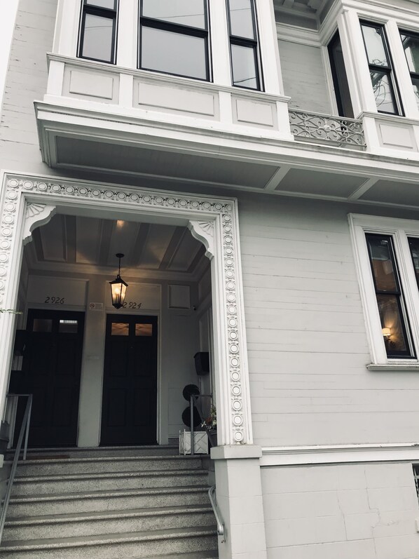 A white building with a grand entrance, a staircase, and a balcony.