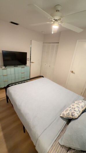 A bedroom with a bed, a television on a cabinet, a ceiling fan, and a wardrobe. -  Stylish Beach House! Newly renovated! 2-1 home! Location Location (Vero Beach)