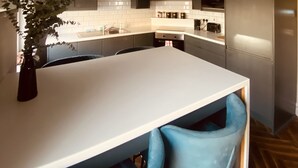 A modern kitchen with dark cabinets, a white countertop, and a blue chair. - 3 BEDROOM APARTMENT BESIDE THE CASHEL PALACE HOTEL (Cashel)