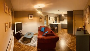 A modern living room with a red sofa, a flat-screen TV, and a herringbone-patterned floor. - 3 BEDROOM APARTMENT BESIDE THE CASHEL PALACE HOTEL (Cashel)