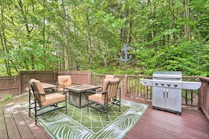 Relax and dine on the deck, surrounded by lush greenery, with a grill and comfortable seating for two.