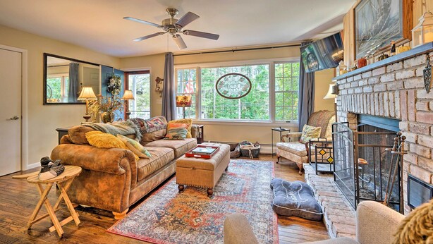A cozy living room with a fireplace, comfortable seating, and large windows. - Rustic Adirondacks Home w/ Hot Tub & Lake Access! (Chestertown)