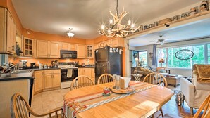 A spacious kitchen with wooden cabinets, a large island, and a chandelier. - Rustic Adirondacks Home w/ Hot Tub & Lake Access! (Chestertown)