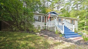 A house with a porch, a flag, and a staircase leading to the front door. - Rustic Adirondacks Home w/ Hot Tub & Lake Access! (Chestertown)