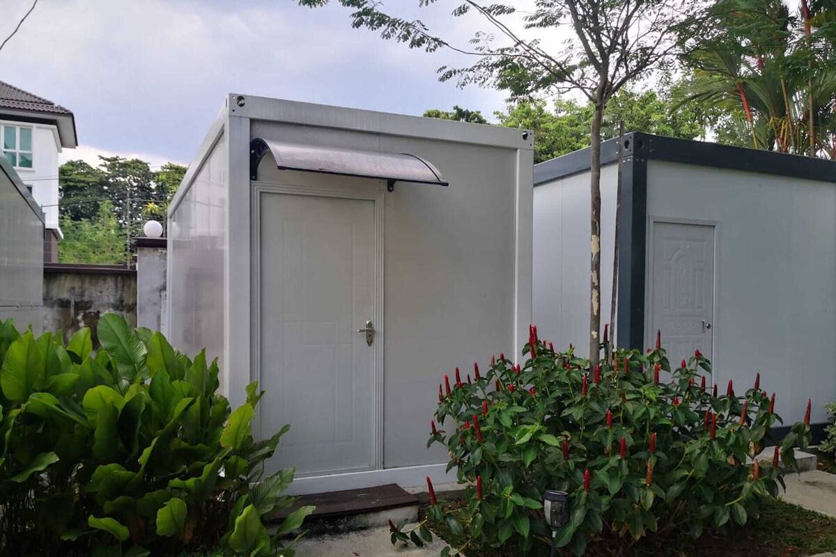 Un bâtiment compact, de plain-pied, avec une porte fermée et un petit auvent.