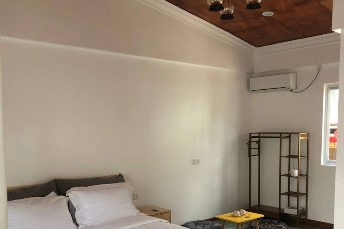 Une chambre avec un grand lit, un plafond en bois et une petite table avec une chaise.